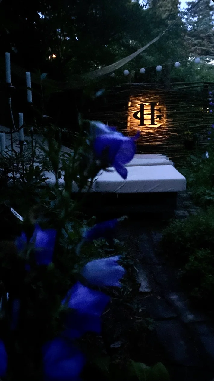 Glowing HG monogram at the end of a softly lit garden path after sunset
