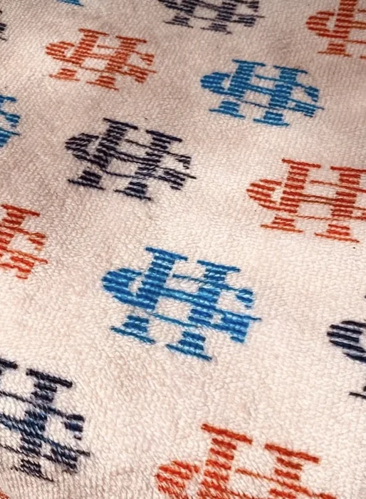 Repeated HG logo pattern on cream-colored fabric